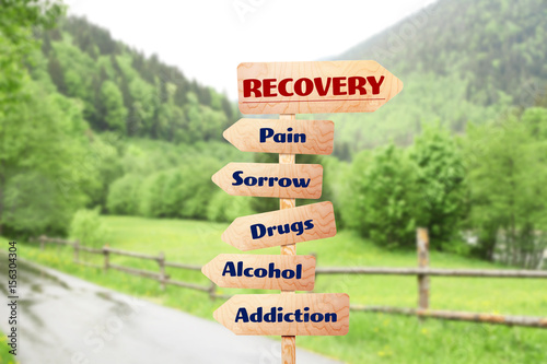 Rehabilitation concept. Wooden signboards pointing different directions to RECOVERY and ADDICTION on landscape background photo