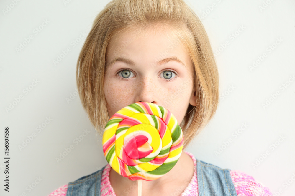 Funny teenager girl holding colourful lollipop on white background