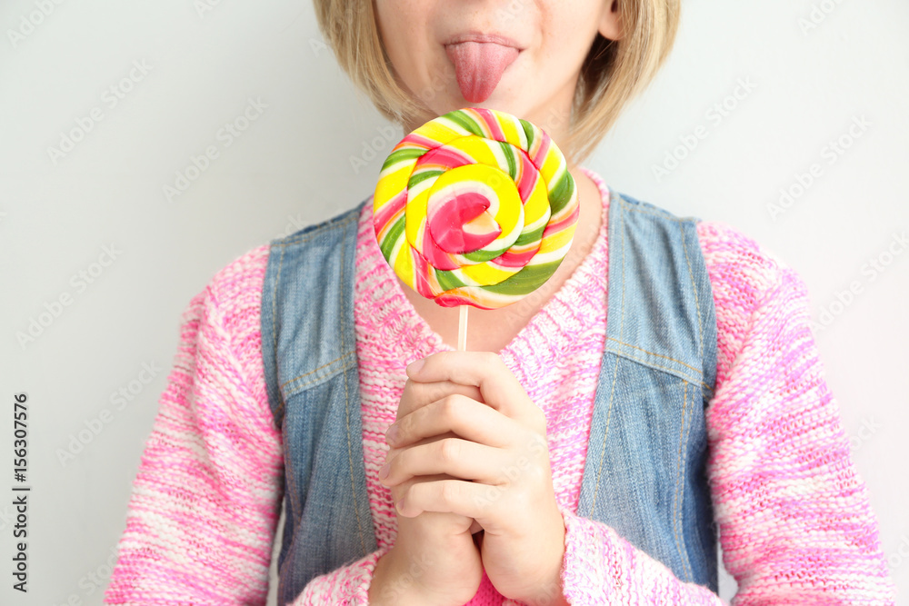 Funny teenager girl holding colourful lollipop on white background