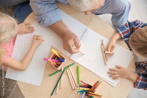 Senior man painting together with grandchildren at home