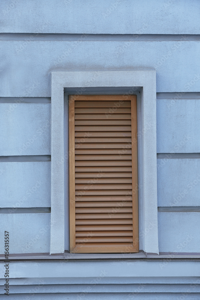 Window with closed blinds on old blue building