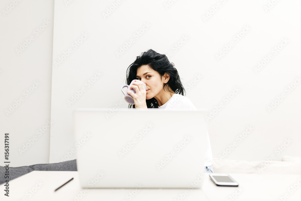 Woman working with her laptop while drinking coffee Woman working with her laptop while drinking coffee