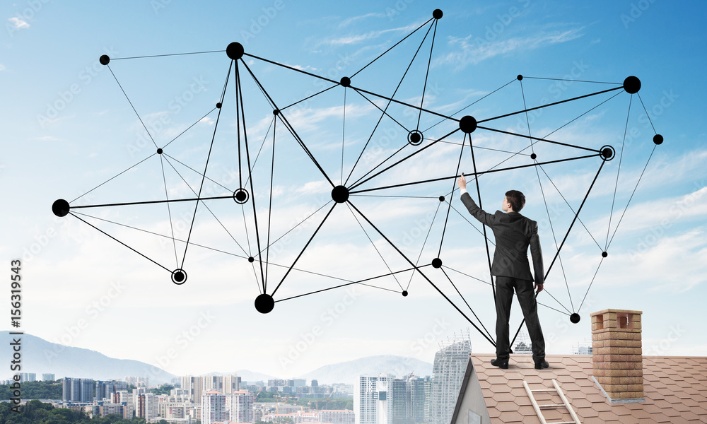 Businessman on house roof presenting networking and connection concept. Mixed media Businessman on house roof presenting networking and connection concept. Mixed media