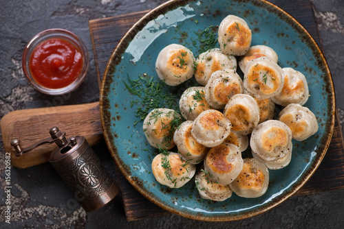 Foto Turquoise plate with fried russian meat dumplings pelmeni, flat-lay, close-up