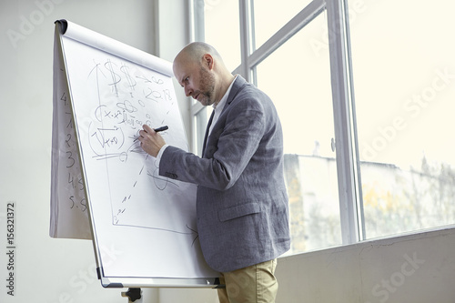 Bald Man Drawing an Arrow on the Board During a Lecture