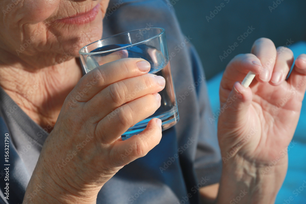Elderly woman taking pill at home, closeup Elderly woman taking pill at home, closeup