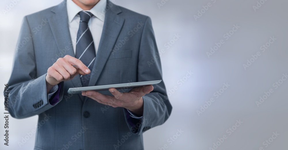 Businessman holding tablet with grey lights background Businessman holding tablet with grey lights background