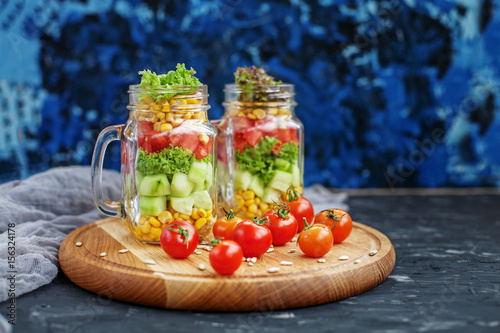 Salad with tomatoes and corn and cucumbers and lettuce. Wooden boards. Healthy food, Diet, Detox, Clean Eating or Vegetarian concept