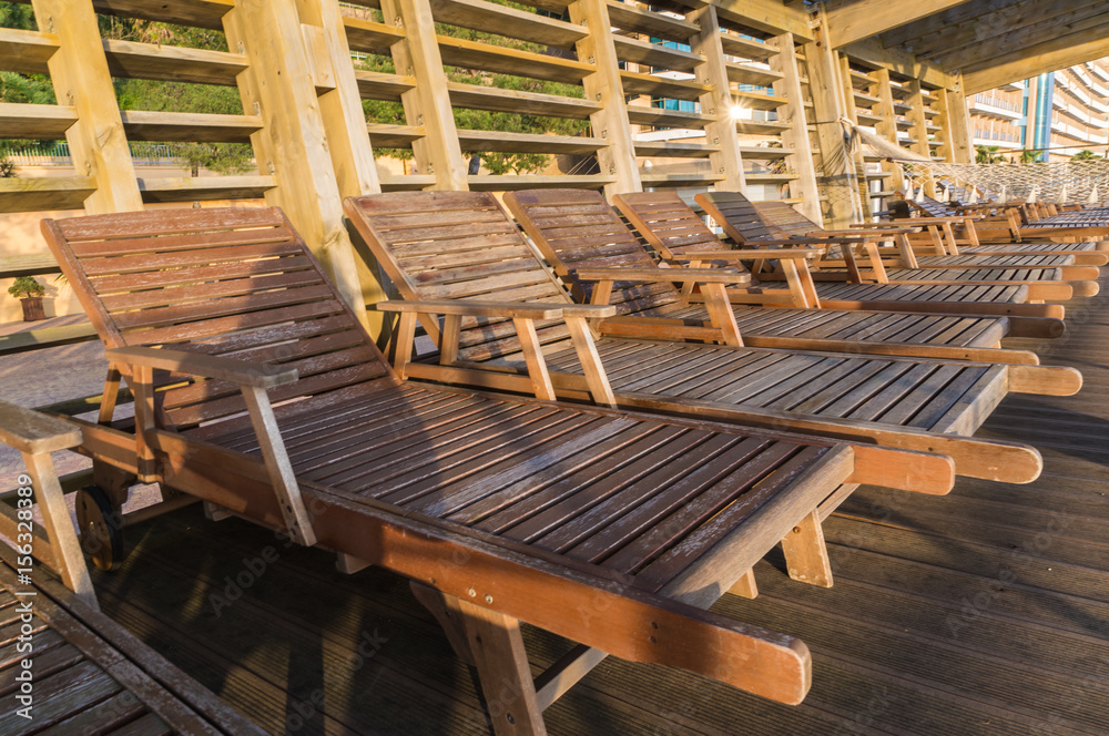 Vacation , beach concept. Wooden sunbeds on the beach, near the sea, summer season is just beginning. Vacation , beach concept. Wooden sunbeds on the beach, near the sea, summer season is just beginning.