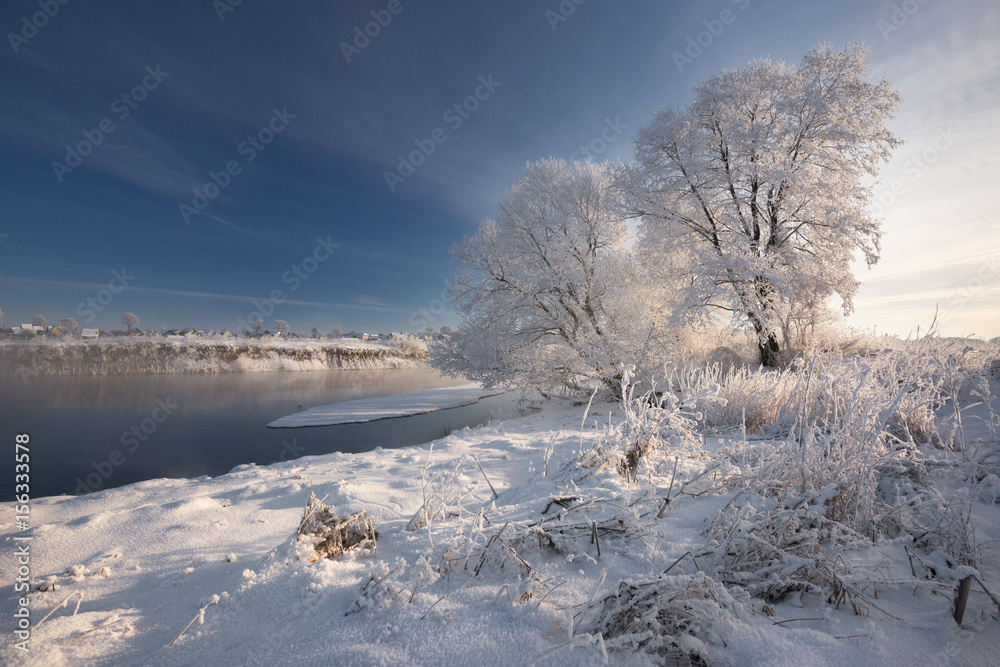 A Real Russian Winter. Morning Frosty Winter Landscape With Dazzling White Snow And Hoarfrost,River And Saturated Blue Sky. Foggy River Bank With Frost-Covered Trees And Crispy Reeds In The Frost.