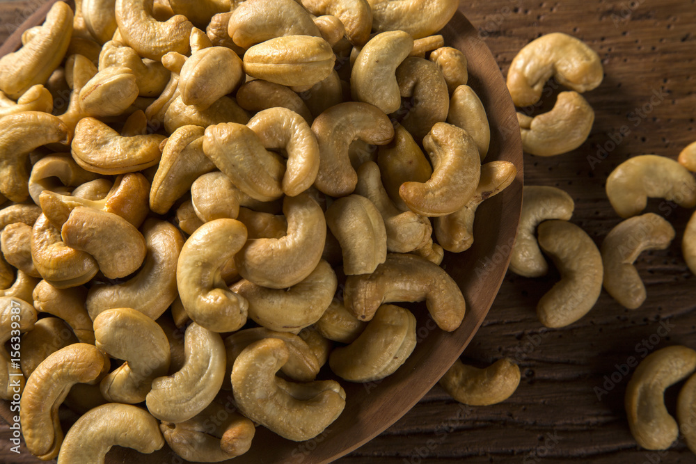 Cashew nuts in wood bowl on wood background Cashew nuts in wood bowl on wood background