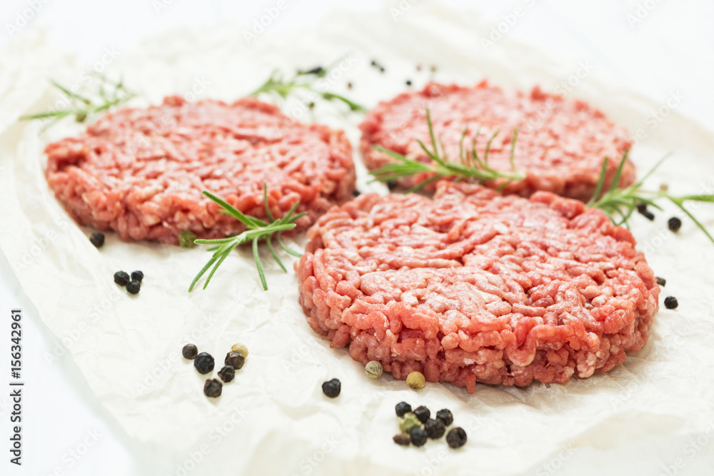 Raw hamburgers without fat from organic beef on a white wooden background with spices. High quality minced meat.