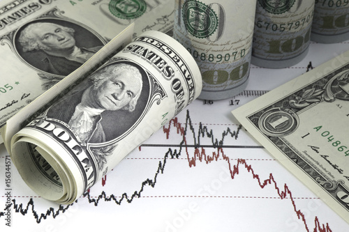 Diagram of stock market prices rates. One us dollar bills, rolled hundred us dollar bills. Ruler on the chart. Red and black lines on the graph.