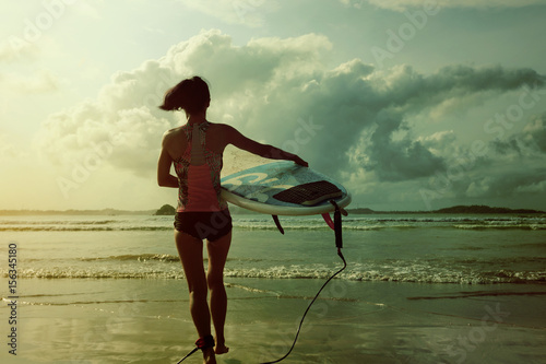 young woman surfer ready to surf on a beach