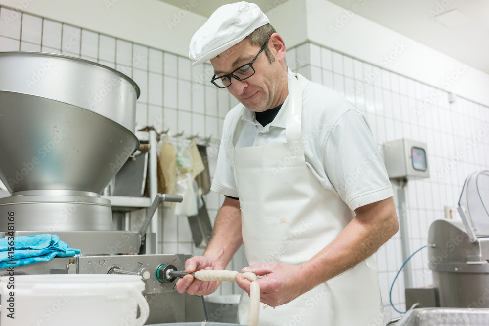 Butcher filling sausages at machine Butcher filling sausages at machine