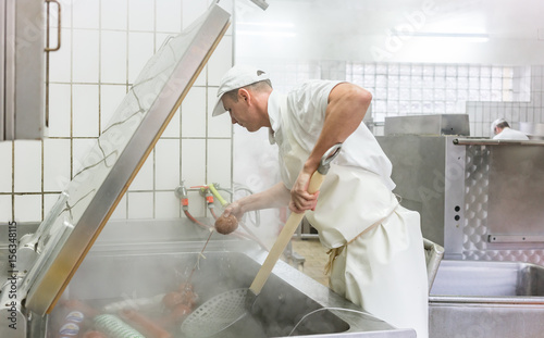 Fleischer kocht Würste im Kessel und stellt so Brühwurst her photo