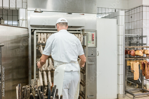 Fleischer bereitet Wurst und Fleisch zum Räuchern vor photo