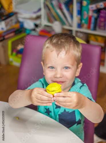 cute little boy showing hand made plasticine muffin