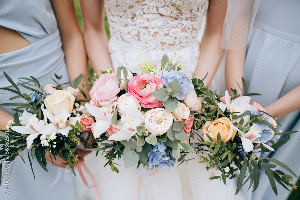 Bride and bridesmaid holding in the hands bouquets of beautiful fresh flowers Bride and bridesmaid holding in the hands bouquets of beautiful fresh flowers