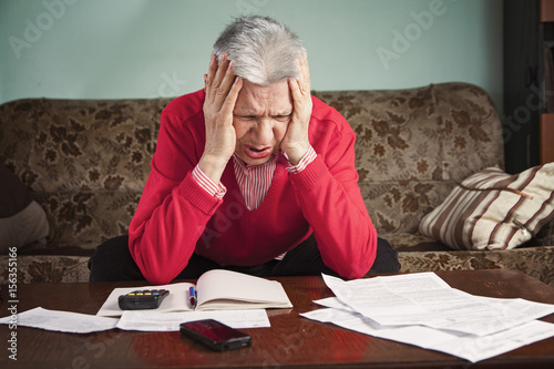 Obraz na plátně Senior old woman desperate over the bills she has to pay, worried and with heada