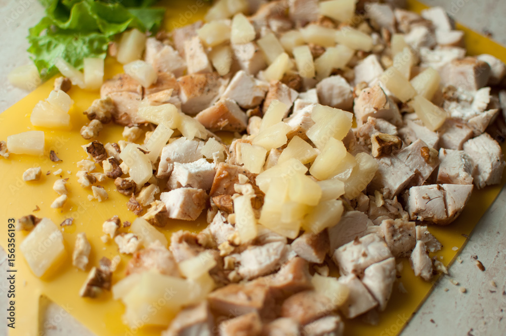 Chopped ruddy chicken breasts with leaf salad and crushed walnut on yellow cutting board. Chopped ruddy chicken breasts with leaf salad and crushed walnut on yellow cutting board.