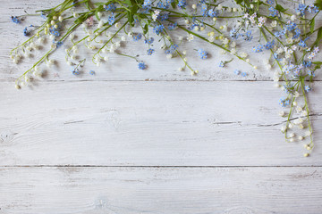 Spring flowers of lilies of the valley, forget me not  on a wooden background