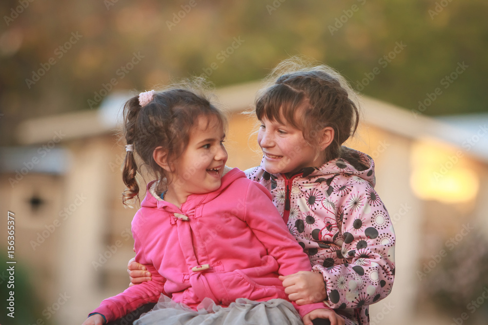 outdoor portrait of two young happy children, girls - sisters - playing in park on natural background outdoor portrait of two young happy children, girls - sisters - playing in park on natural background