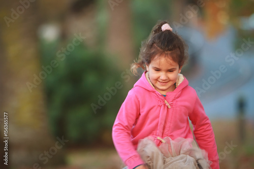 outdoor portrait of young happy child girl playing in park on natural background