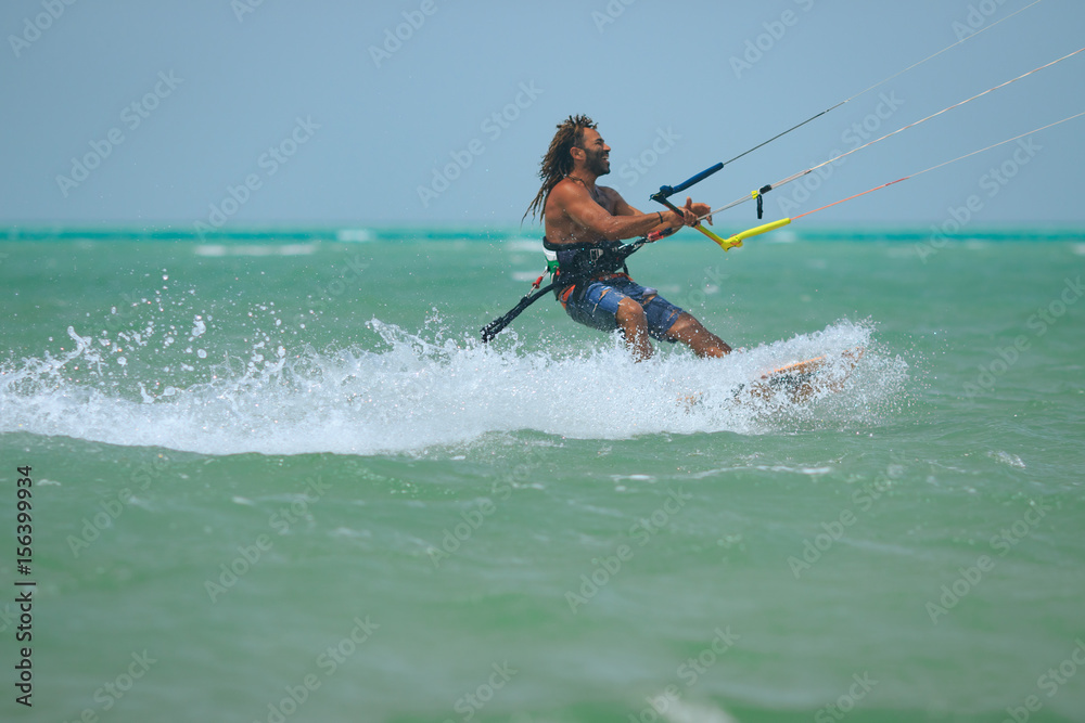 Kite surfer rides waves of the blue lagoon with kite flying in sky. Recreation activity and active extreme water sports kiteboarding, hobby and fun in vacation time, blue sea water, Egypt, Red Sea Kite surfer rides waves of the blue lagoon with kite flying in sky. Recreation activity and active extreme water sports kiteboarding, hobby and fun in vacation time, blue sea water, Egypt, Red Sea
