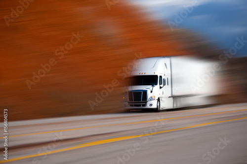 White big semi truck on the road on blurred colors background