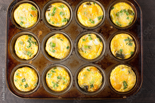 
Tin Muffin Pan of cooked Egg Muffin Cups with broccoli, onion, and cheese distant view 
