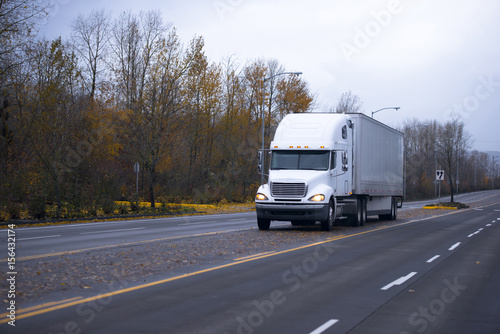 White semi truck and trailer on autumn road