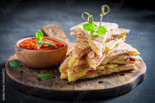 Spicy quesadilla made of tortilla with sauce and herbs photo