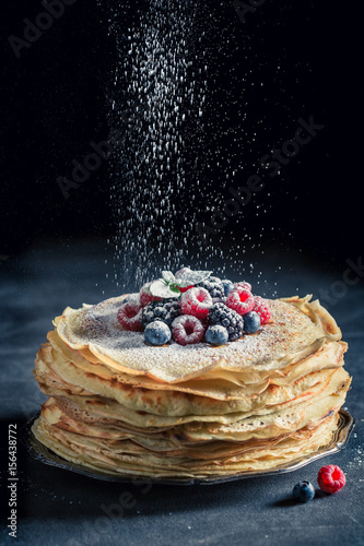Tasty stack of pancakes with berries and powder sugar