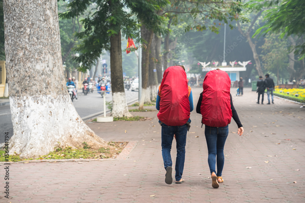 Travelers with red backpacks waking on Hanoi street