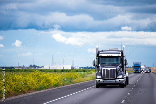 Dark semi truck with traffic on road in California