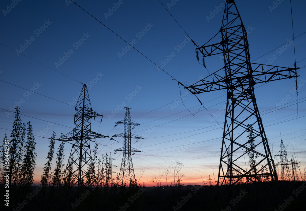 High voltage electricity pylons against sunset. Electric pole power lines and wires.