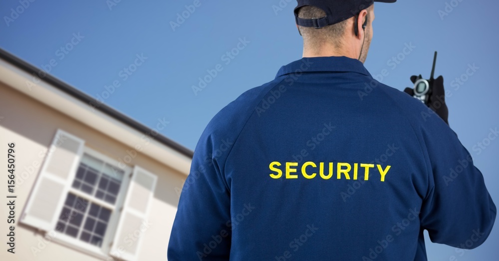 Obraz premium Security man in front of a house holding a talkie-walkie