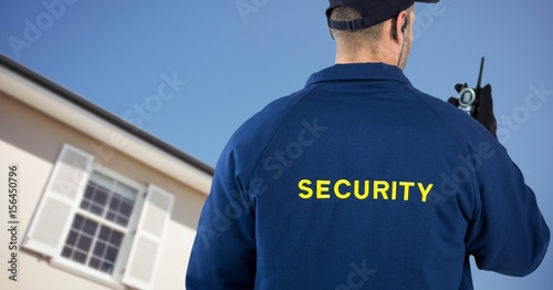 Security man in front of a house holding a talkie-walkie