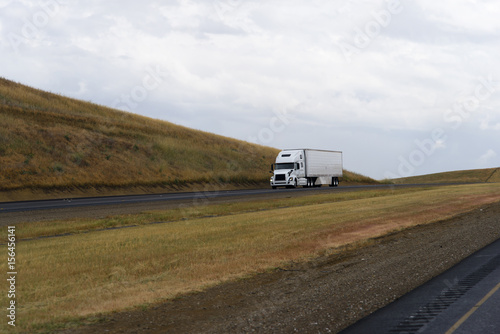 White semi truck driving on California hills highway road