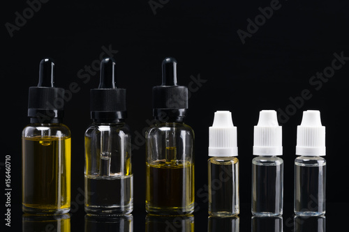 Six containers with aromatic liquids on a black background with reflections