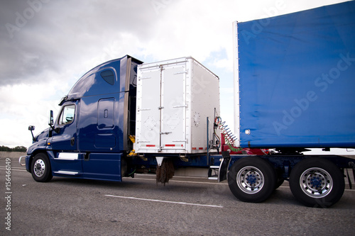 Dark blue semi truck with storage container and trailer