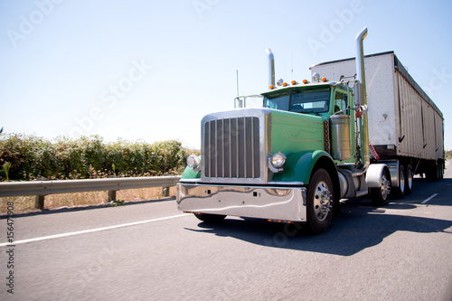Big rig attractive green semi truck with bulk trailer