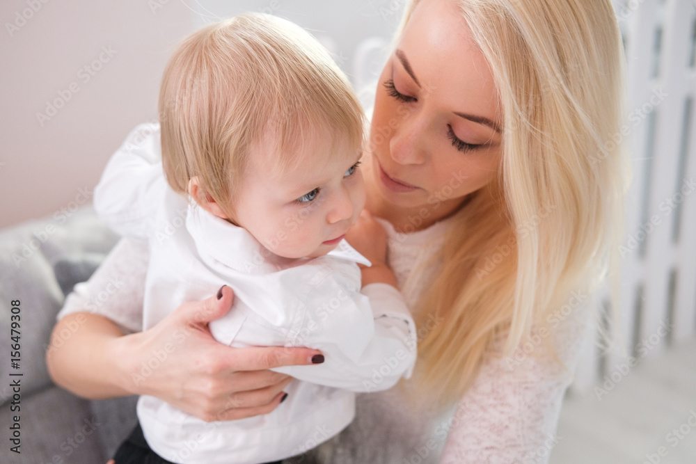 young mother holding a baby daughter in her arms and kisses her in the nursery young mother holding a baby daughter in her arms and kisses her in the nursery