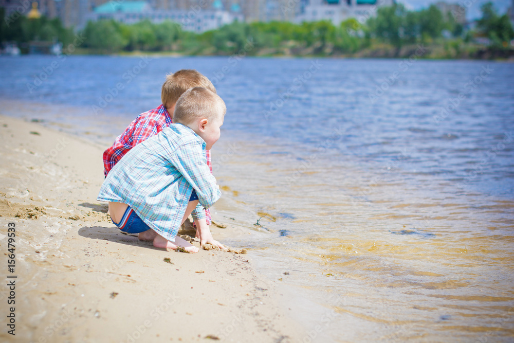 Kids boys playing on a beach near river with water and sand felling happy