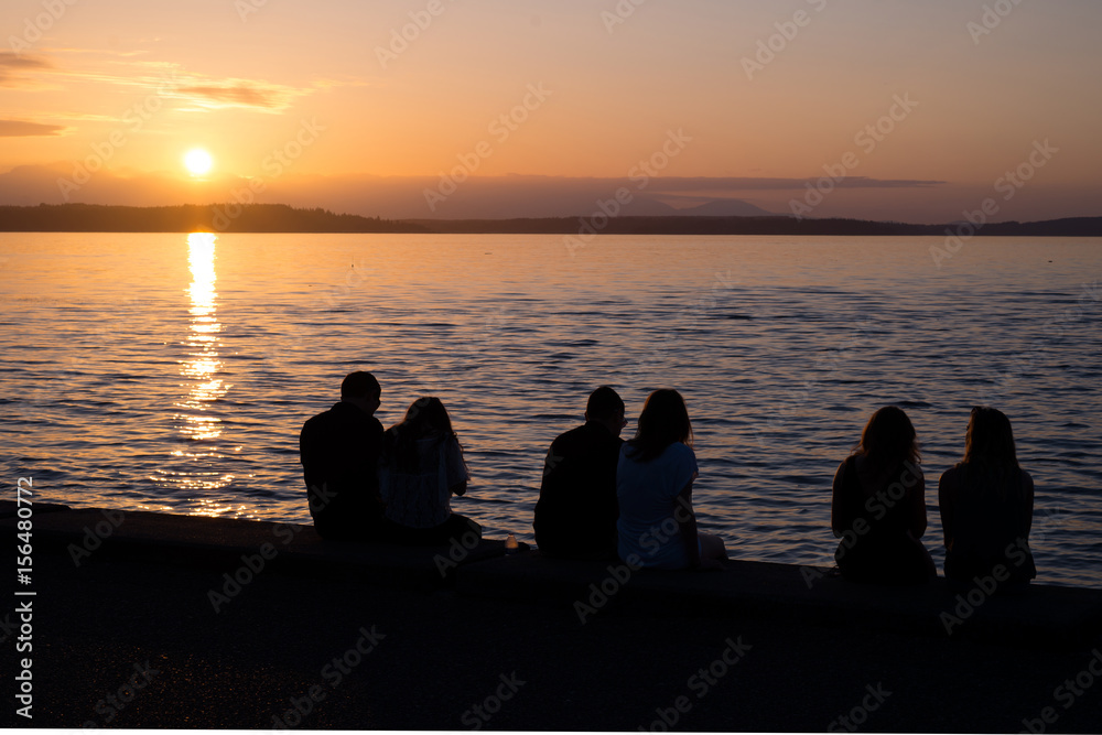 Silhouettes of couples sitting on the beach at sunset