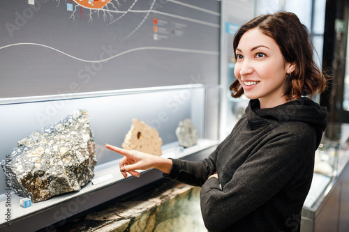 Beautiful Asian happy geologist woman indoors looking at minerals collection, education and science concept