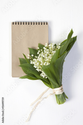 bouquet of lilies of the valley with a notepad for notes. Copy space