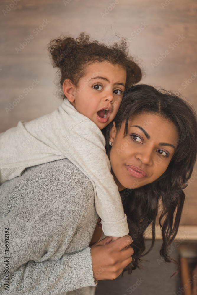Fototapeta premium little daughter hugging mother while spending time at home
