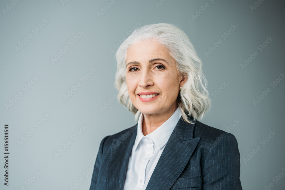 portrait of smiling senior businesswoman in suit isolated on grey portrait of smiling senior businesswoman in suit isolated on grey